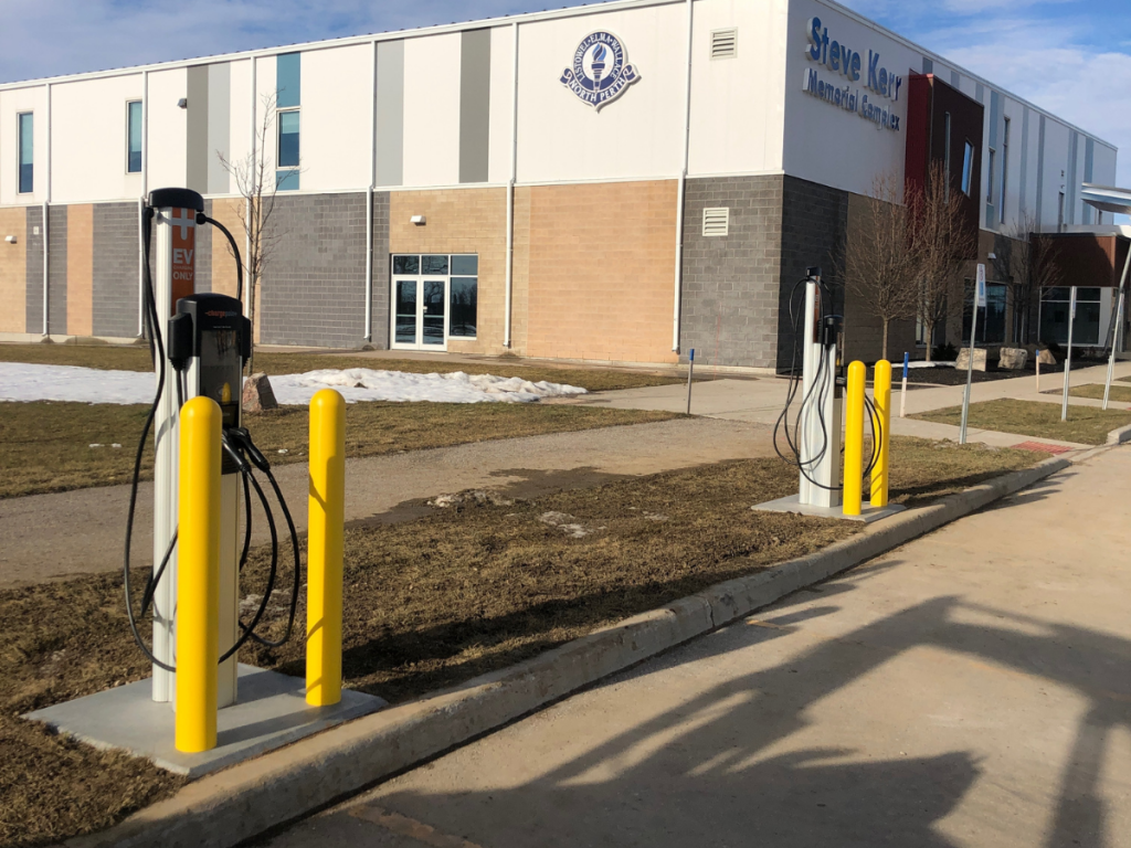 Electric vehicle charging stations outside a municipal building with the text 'Municipalities' inviting visitors to learn more about ChargerCrew's services for the municipal industry.